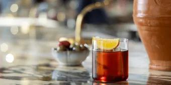 Negroni at Apéro Bar A clay vase next to a delicious drink on a bar top. The drink is a Negroni.