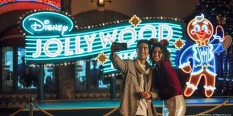 Disney Jollywood Nights at Disney's Hollywood Studios A couple taking a selfie in front of a neon sign for Disney Jollywood Nights