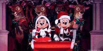 Mickey and Minnie in Santa outfits on a sleigh in front of reindeer