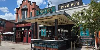 An irish pub with a sign saying Raglan Road Irish Pub, there is a bar and multiple bar stools.