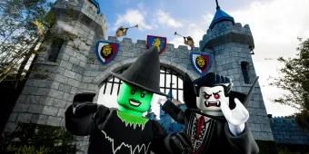 A lego green witch and a lego vampire at the gates of a castle.