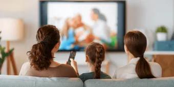 US TV Favorites A woman, a teenager and a young girl watching TV from a sofa