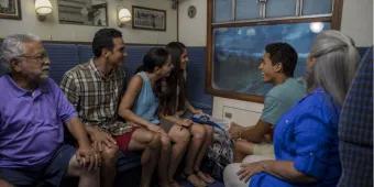 A multigenerational family riding the enclosed Hogwarts Express attraction at Universal Orlando Resort, enjoying the scenic views outside the compartment window, a perfect activity when it's raining.