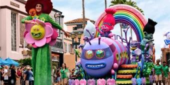 Trolls characters on a vibrant, rainbow-themed parade float entertaining crowds at Universal Orlando Resort, illustrating a time-efficient way to see multiple characters during a busy one-day itinerary.