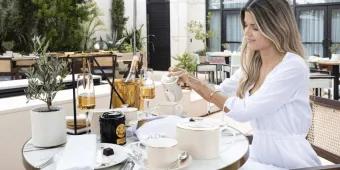 Woman dining outside on terrace pouring a drink