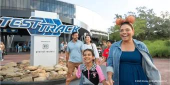 A happy family laughing together while walking past the Test Track attraction at EPCOT, Walt Disney World in Florida