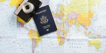 A US passport and camera resting on a world map, representing international travel, planning, and the major trends defining US travel in 2026.