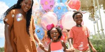 A joyful family surrounded by colorful Disney-themed balloons and bubbles at Walt Disney World