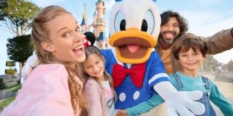 A happy family meeting Donald Duck at Disneyland Paris with the iconic castle in the background.