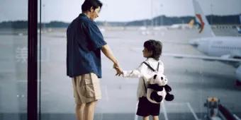 A father and son looking out the window at an airport