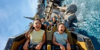 Riders laughing and screaming as their coaster splashes through water on Hiccup's Wing Gliders, Isle of Berk