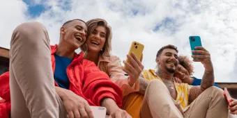 Group of friends using their smartphones while laughing.