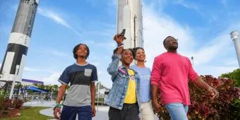 A family walking past large rockets at the Kennedy Space Center Rocket Garden