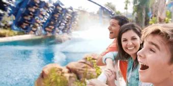A family laughing and cheering as Manta roller coaster splashes down beside them at SeaWorld Orlando
