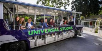 Guests smiling and waving from the Universal Studios electric tram during the studio tour