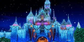 Sleeping Beauty Castle at Disneyland Resort glowing at night with shimmering icicle lights, holiday wreaths, snow-capped turrets, and falling snow effect
