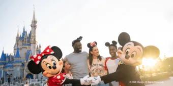 A family posing for a picture with Mickey Mouse and Minnie Mouse in front of Cinderella Castle