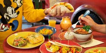 Table filled with colorful Mexican dishes including tacos, salmon, rice, and chili at La Cantina