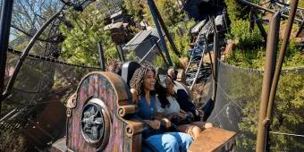 Two women smiling while riding the Curse of the Werewolf roller coaster