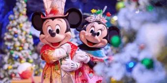 Mickey and Minnie Mouse wearing festive holiday outfits posing in front of snow-flocked Christmas trees
