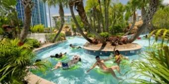 Lazy River in Universal Cabana Bay Beach Resort with several happy-looking guests floating on the water under palm trees