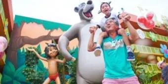 Father and son smiling while next to Jungle Book character statues