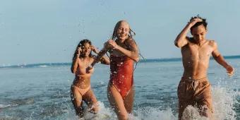 Three friends laughing and splashing in the sea on a summer holiday.