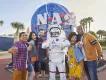 Kennedy Space Center A group of 5 friends posing with someone in an space suit in front of the NASA logo
