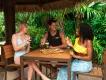 All-Inclusive Verpflegung in Discovery Cove Ein Mann und zwei Frauen sitzen um einen Tisch, auf dem zwei Pizzen liegen. Die Frauen halten Weingläser in der Hand und vor dem Mann steht ein Glas Bier.