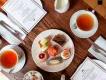 Mother's Day Afternoon Tea A birds eye view of a table with two cups of tea, a plate of cakes and an afternoon tea menu
