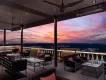 Dining in Orlando A terrace with sofas, tables and chairs looking out over a purple and pink toned sunset