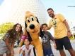 Walt Disney World Resort in Florida  A mother and father with a young boy and young girl posing with Pluto in front of Spaceship Earth