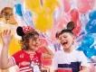 Walt Disney World Resort in Florida A young girl wearing a headband with Minnie Mouse ears and a young boy wearing a hat with Mickey Mouse ears standing in front of multi-coloured balloons