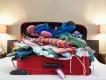 Packing for your Orlando Holiday A red suitcase on top of a bed overflowing with clothes