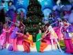 Christmas at Universal Orlando Resort Performers dressed as Whos from the Grinch wearing bright coloured clothes and exchanging gifts in front of a large Christmas tree