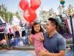 Kids Attractions at Disneyland Resort in California A man holding a young girl who is carrying a balloon standing in front of Dumbo the Flying Elephant