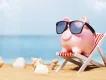 Orlando on a Budget A pink piggy bank wearing sunglasses and sitting on a deck chair on a beach