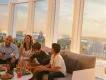 Bar 17 Bistro A man, woman and two children talking and laughing at a rooftop bar. They are sat on a sofa overlooking Volcano Bay and Cabana Bay Hotel
