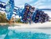 Manta Roller Coaster at SeaWorld Orlando Ride shaped like manta ray in motion, curving round bend on top of lake with water being sprayed up towards the riders