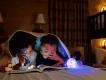 Disney Resort hotels Two young boys reading a book using a torch while lying under the covers on a bed