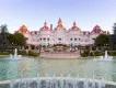 Disneyland Hotel The exterior of a pink hotel behind a fountain and a flower bed in the shape of Mickey Mouse