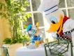 Walt Disney World Dining Reservations Donald Duck dressed as a chef leaning down to greet a child sat at a table wearing a Donald Duck hat