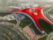 Yas Island A large red building shaped in a triangle with a large yellow badge on it with a black horse on top which is the Ferrari badge. There are roads and rollercoasters coming out of this large building.