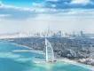 Dubai skyline View from over the crystal clear sea with a view of the beach with an island off of it with a sail shaped building on it called the Burj Al Arab. In the background you can see a view of the city skyline and the Burj Khalifa.