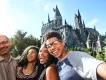 Hogwarts Castle  Selfie of family of four stood on bridge in front of the Hogwarts Castle. There is a boy holding the camera, besides him is a young woman, an older woman and an older man. All are smiling with joy.