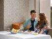 Couple dining in Orlando Couple sat smiling at one another next to each other at a table with a white tablecloth, delicious food and glasses of wine.