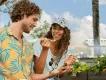 EPCOT Food & Wine Festival Girl smiling holding a plastic fork with food on it looking at a man who is holding the small food portion. In the background the monorail is driving past.