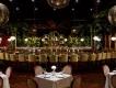 Corazón by Baires, image by Dylan Cross Dark restaurant with long table and yellow bar stools sat looking at wall decorated with plants. There are also matching small restaurant tables. There are also huge glitter balls hanging overhead.