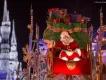 Der Weihnachtsmann im Magic Kingdom Park Der Weihnachtsmann auf einem Paradewagen voller Geschenke. Im Hintergrund ist das Cinderella Schloss in weißem Licht zu sehen.