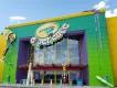Crayola Experience Large modern building coloured yellow, green and purple has big sign saying Crayola Experience on it. There are giant crayons outside with faces on them.